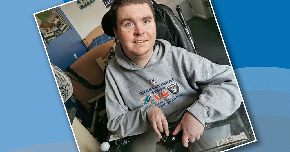 Smiling young man in wheelchair holding modified controller