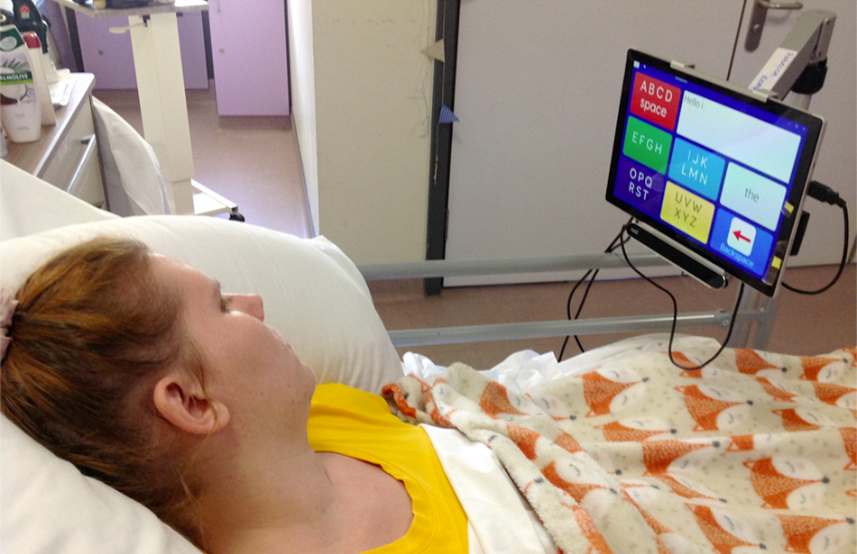 girl in bed looking at computer with letter grid screen