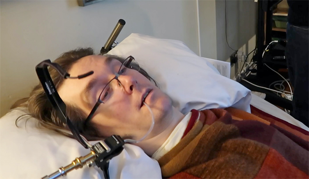 Man in bed using sip and puff switch and voice control