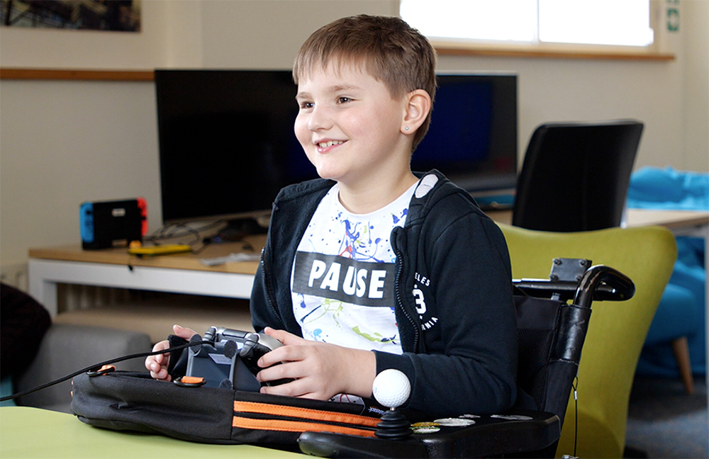 Smiling seated girl using adapted games controller