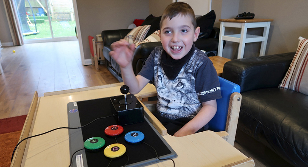 smiling seated boy with adapted games controller