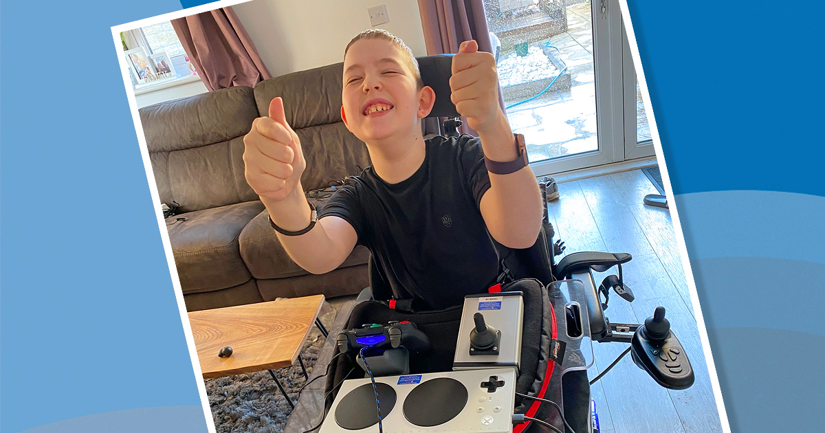 smiling boy in wheelchair with adapted gaming setup gives thumbs up