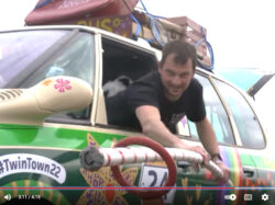 Man leans out of car window to hook a hoop with a pole