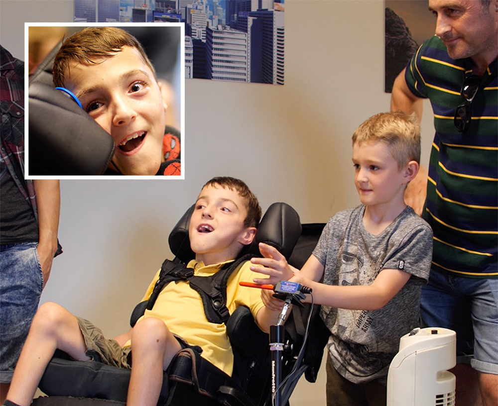 boy helps boy in wheelchair to operate a switch