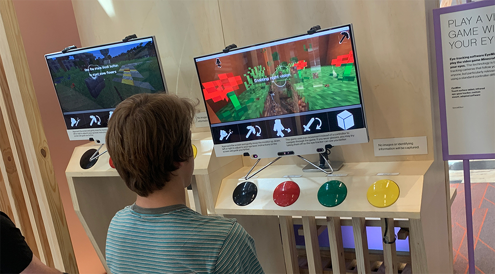 Man sitting in front of screen, which has four large buttons in front