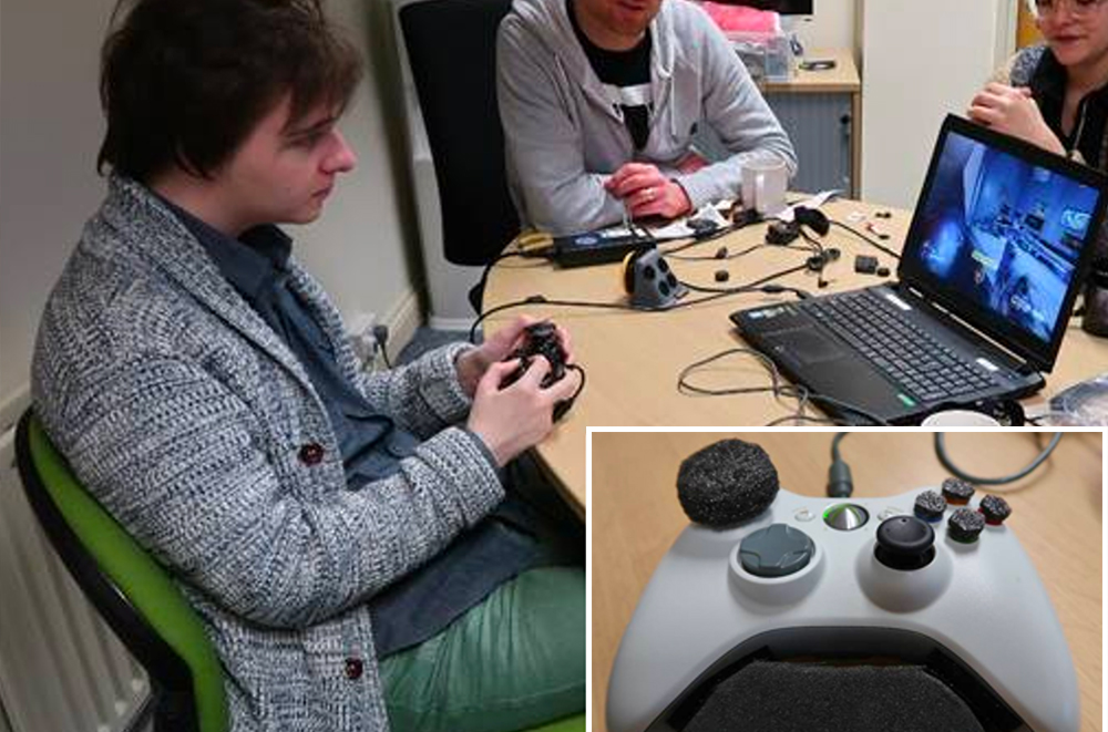 Seated young man using adapted gaming controller