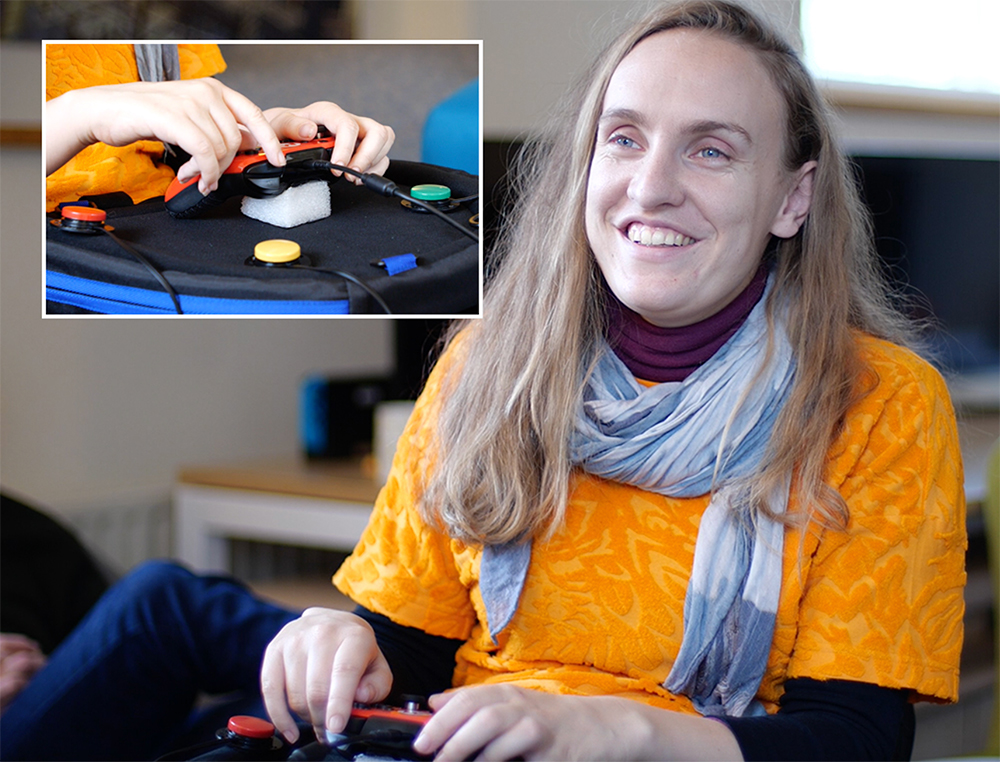 Smiling seated woman using adapted gaming controller