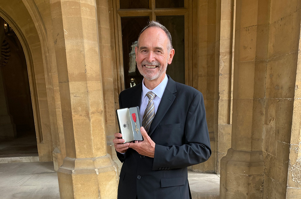 Smiling man in suit holding medal