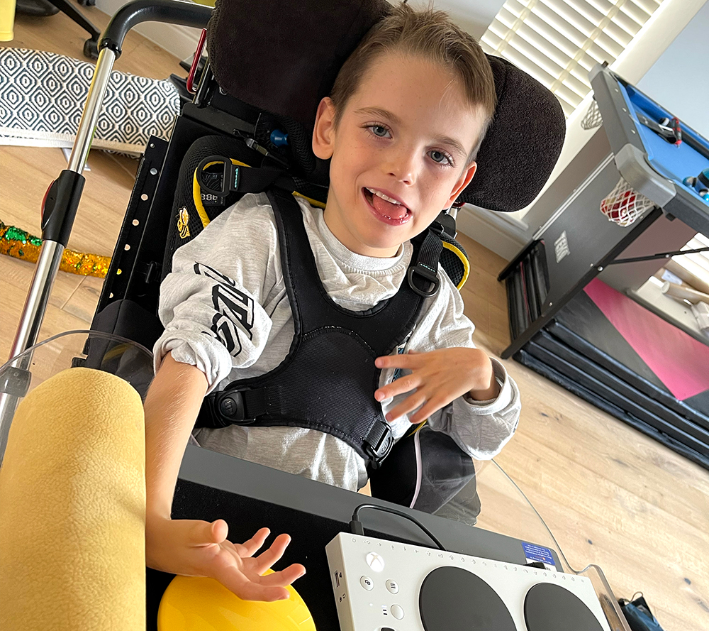 Smiling boy using adapted gaming control setup