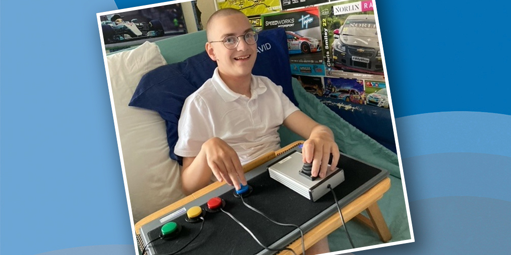 Seated smiling young man using an adapted gaming setup