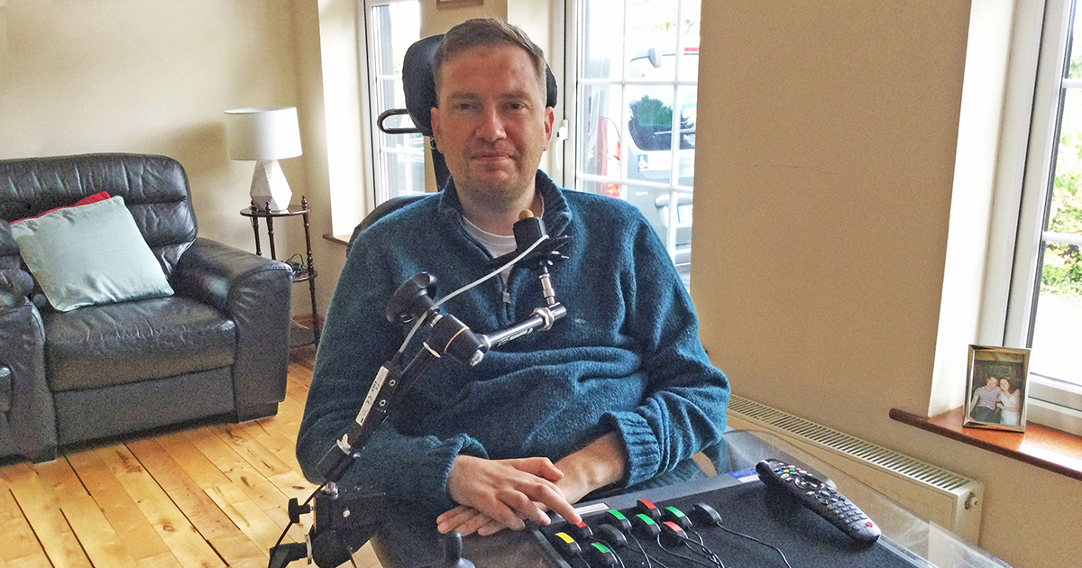 Smiling man in wheelchair with accessible gaming setup