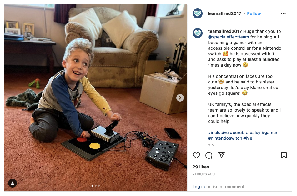 Young smiling boy seated on floor using an adapted gaming controller setup