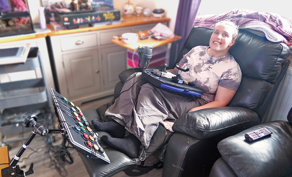 Young woman reclines in a sofa with aboard of foot switches and a lap tray with two joysticks