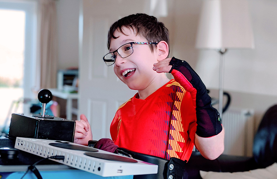 Excited young boy using an adapted gaming controller
