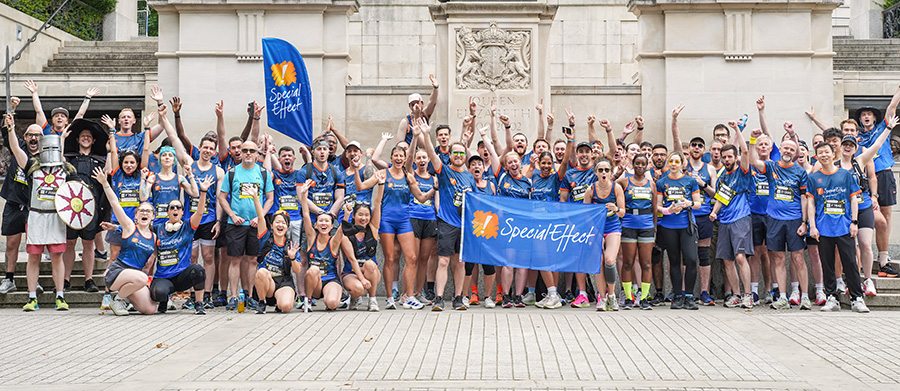 A group of 50-60 runners in SpecialEffect tops cheering.