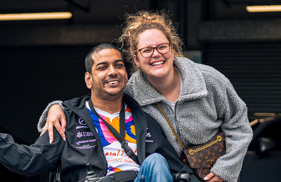 Smiling man in wheelchar next to smiling young woman
