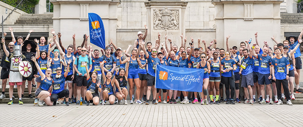 Group of over 50 runners cheering in front of a London memorial